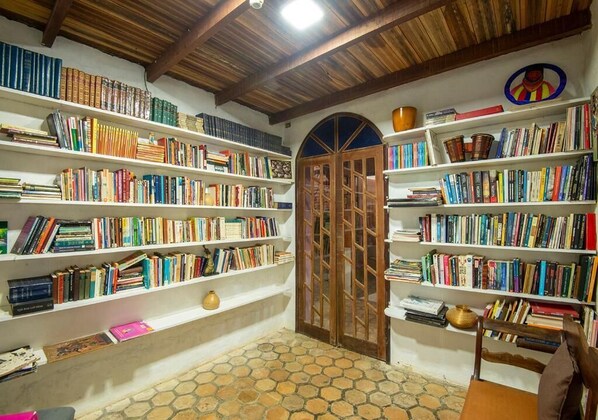 Una biblioteca con estanterías llenas de libros, una puerta de madera y un suelo de baldosas.