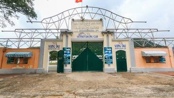 La entrada al Vietnam Racing Club, con una gran puerta verde, una bandera y señalización del club de carreras.