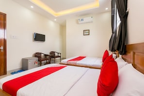 Quarto de hotel com duas camas, televisão, ar condicionado, escrivaninha e uma cadeira.