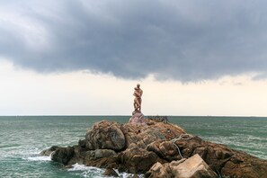 Uma área costeira rochosa com uma estátua em uma grande formação rochosa.