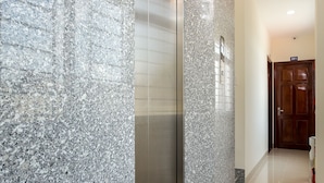 Een hal met een gepolijste granieten muur, een metalen lift en een houten deur met het nummer 501.