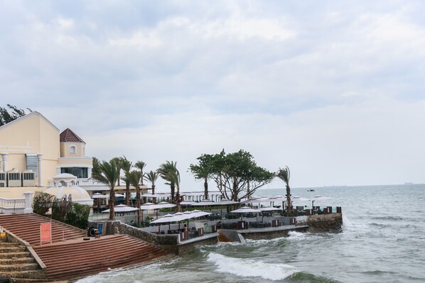 Un hôtel situé sur la côte, doté d’une terrasse avec des places assises extérieures, d’un escalier menant à la terrasse et offrant une vue sur la mer.