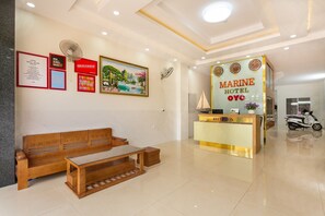 Uma área de recepção com um banco de madeira, balcão de recepção e uma parede com quadros e um relógio.