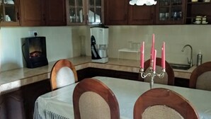 A dining area with a table, chairs, and a chandelier. - Windsor Forest Bungalow (Bandarawela)