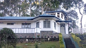 A two-story house with a stone foundation, a blue roof, and a small front yard with potted plants and a staircase leading up to the entrance. - Windsor Forest Bungalow (Bandarawela)