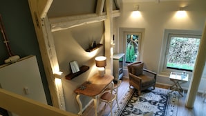 A cozy room with a wooden table, chairs, a rug, and a window with a view of greenery. - Ferienapartments Lüneburger Heide - St. Dionys (Barum)
