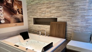 A modern bathroom with a large bathtub, a wooden vanity, and a wall-mounted shelf. - Domus Park Hotel & SPA (Frascati)
