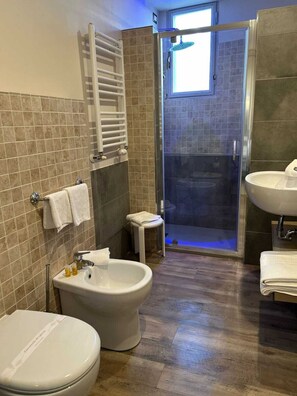 A modern bathroom with a bidet, a sink, a toilet, and a glass-enclosed shower area. - Domus Park Hotel & SPA (Frascati)