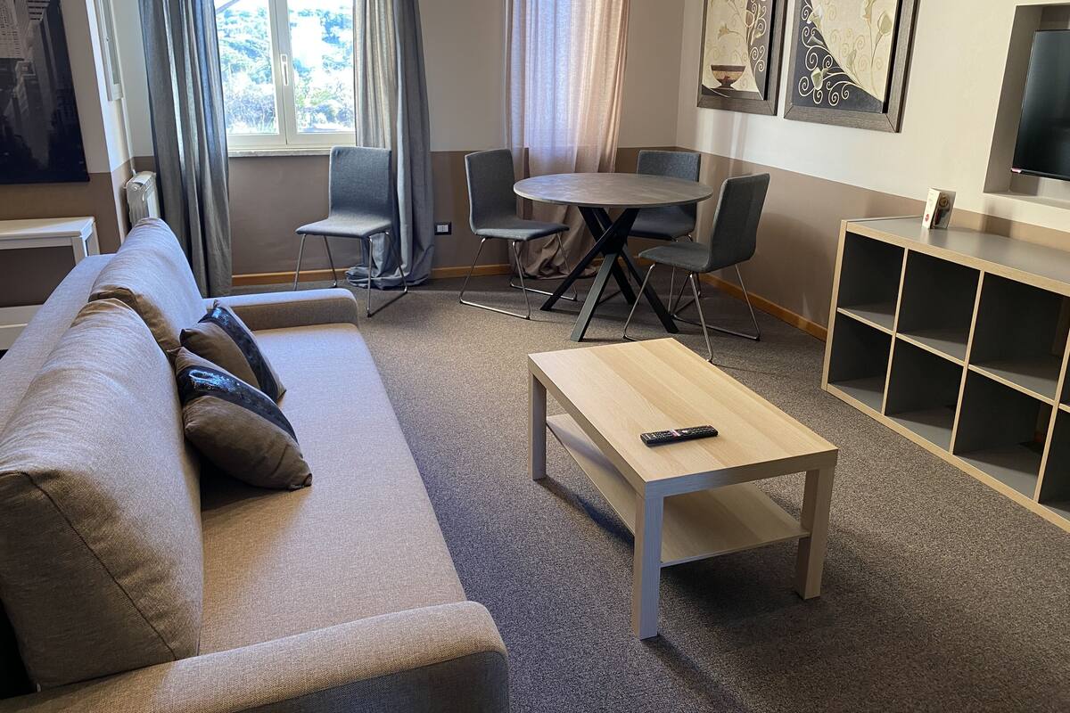 Una sala moderna con un sofá, una mesa de centro y un comedor con sillas y una mesa.