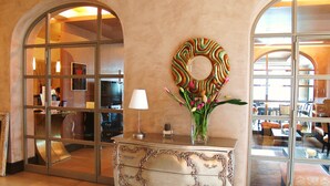 A lobby with a decorative console table, a vase with flowers, and a large mirror. - Domus Park Hotel & SPA (Frascati)