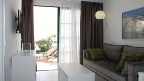 Un salon moderne avec un canapé gris, une table basse blanche et un téléviseur à écran plat fixé au mur.