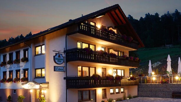 Un hôtel à plusieurs étages doté de balcons, d’une terrasse et d’une enseigne indiquant qu’il s’agit d’un restaurant.