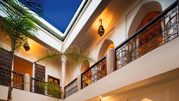A pool area with a clear water surface, surrounded by a tiled deck and a low brick wall. - Riad Darhani (Marrakech)