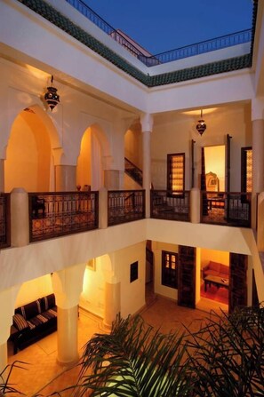 Un interior de varios niveles con corredores abovedados y balcones, con una decoración y luminarias tradicionales.