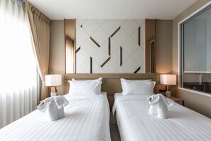 Habitación de hotel con dos camas, un ventanal grande y un diseño geométrico en la pared.