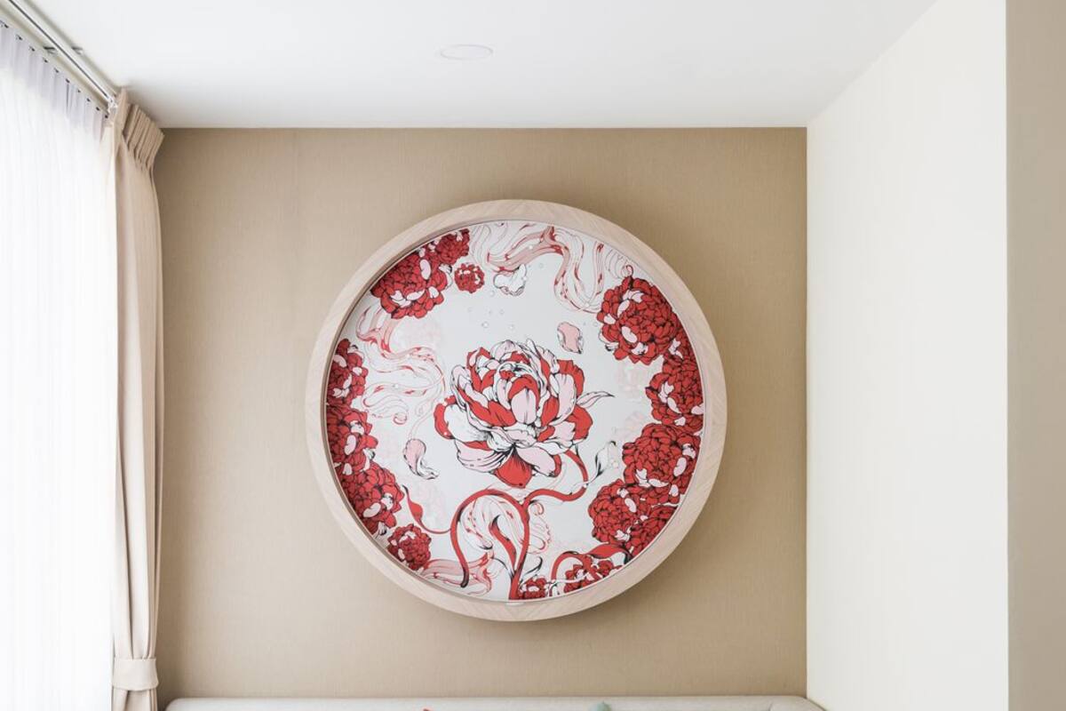 Een moderne woonkamer met een beige bank, twee kussens, een rond kunstwerk aan de muur, een gele stoel en een marmeren vloer.