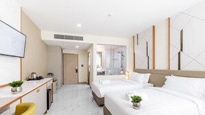 Habitación de hotel moderna con una cama grande, un escritorio con una computadora, una silla y una planta pequeña.