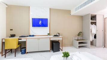 Habitación de hotel con escritorio, televisión, armario y cama con toallas y una planta.