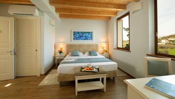 A bedroom with a bed, bedside tables, a window with a view, and a door.