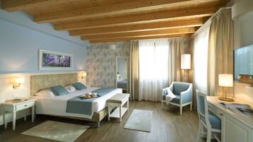 A hotel room with a bed, bedside tables, a desk, a chair, and a TV.