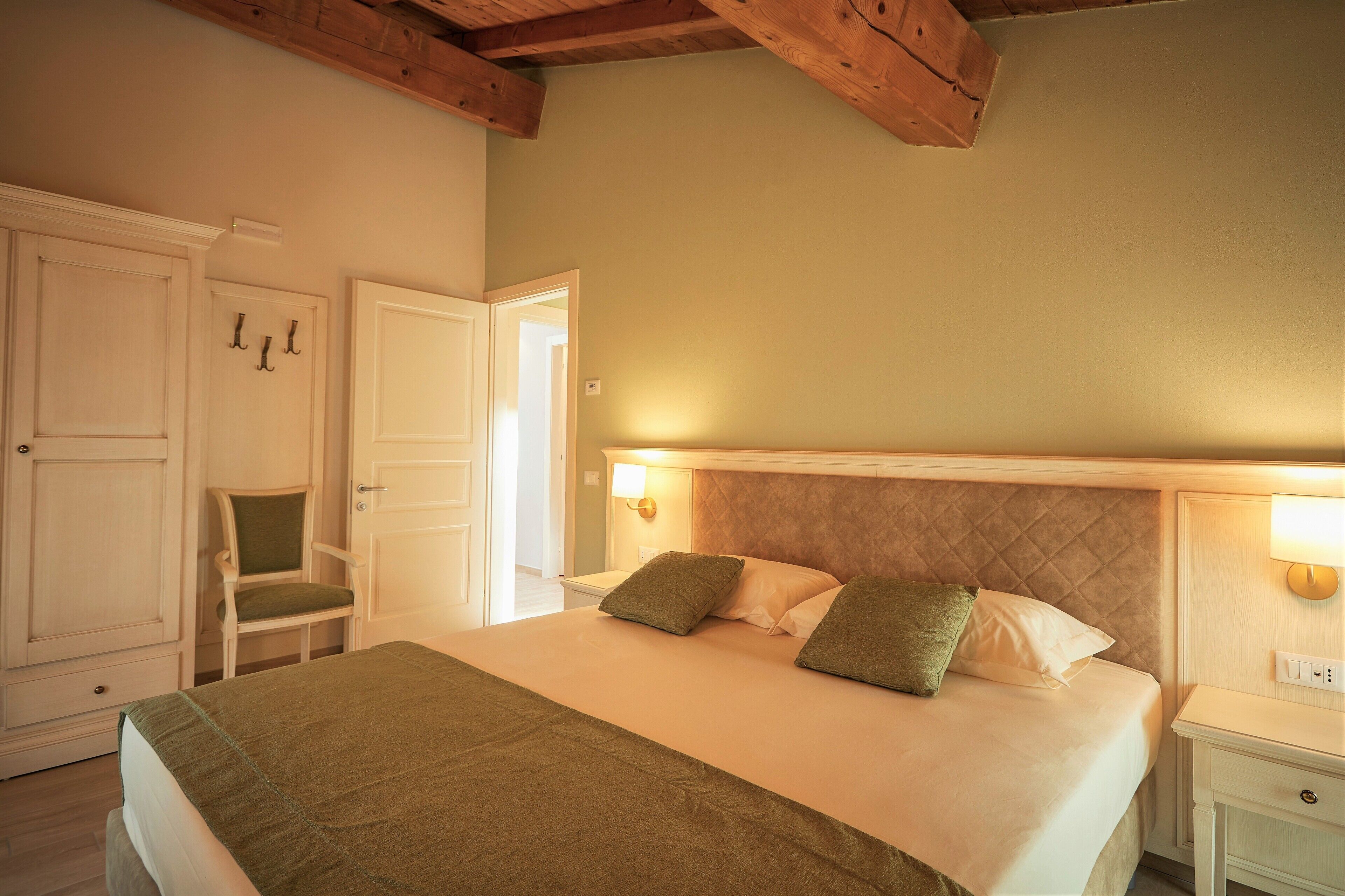 A bedroom with a bed, a chair, a wardrobe, and a nightstand.