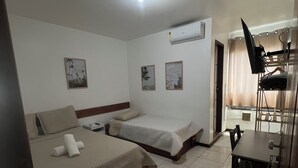 Ein Hotelzimmer mit zwei Betten, einem Schreibtisch, einem Stuhl und einem kleinen Tisch.