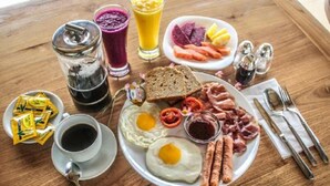 A breakfast plate with eggs, bacon, sausages, toast, and a variety of fruits and vegetables. - Kubu Jamu Ubud (Ubud)