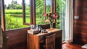 A wooden desk with a vase of flowers, a coffee maker, and a tray with cups and a teapot. - Kubu Jamu Ubud (Ubud)