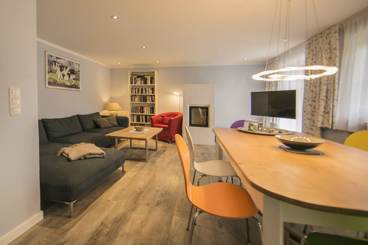 A modern living room with a sofa, a dining table, and a TV.