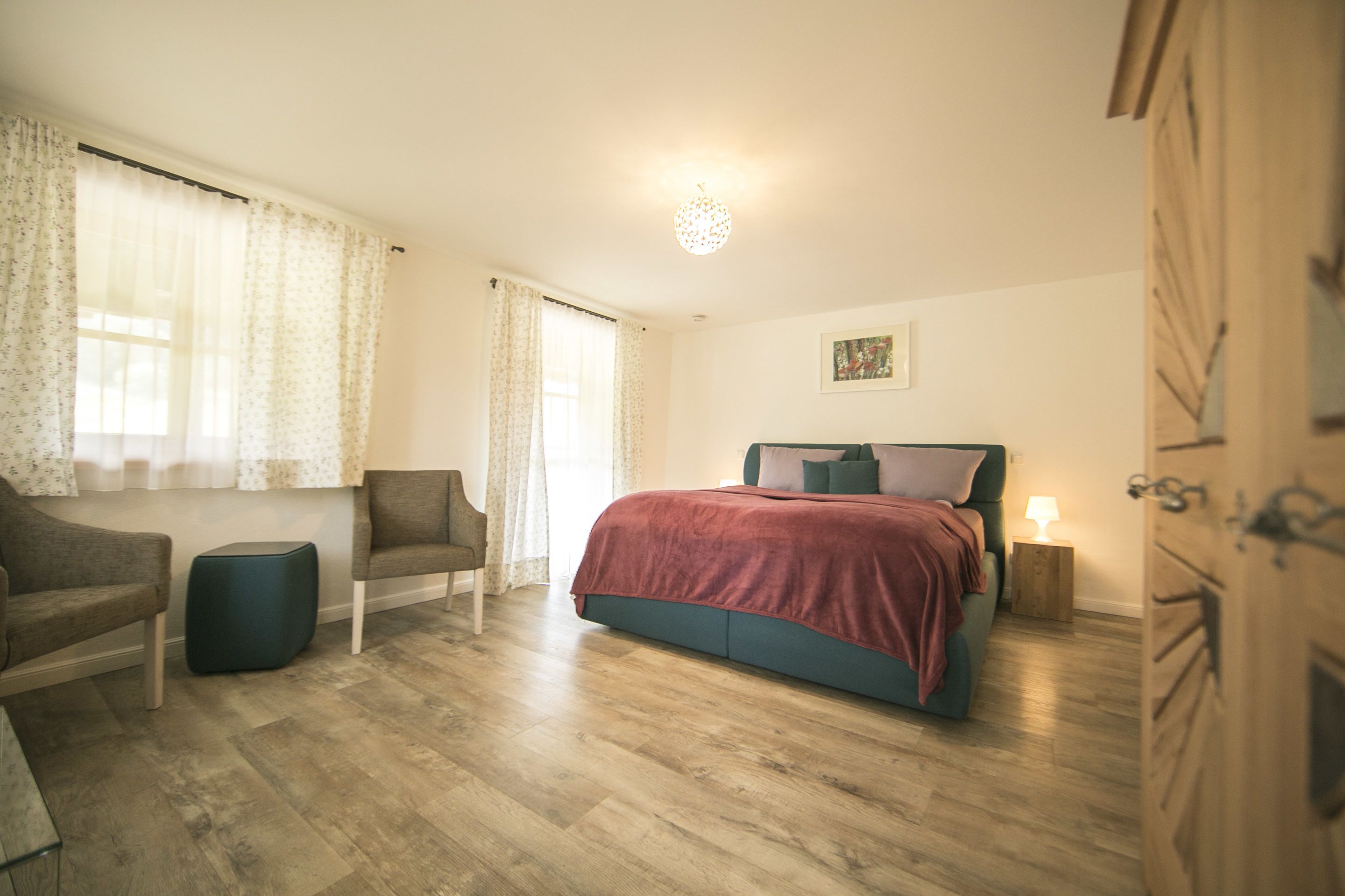 A bedroom with a bed, a chair, a small table, and a wardrobe.