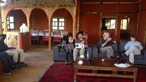 Un intérieur rustique avec un toit de chaume, des arches en bois et un sol recouvert d’une moquette rouge.
