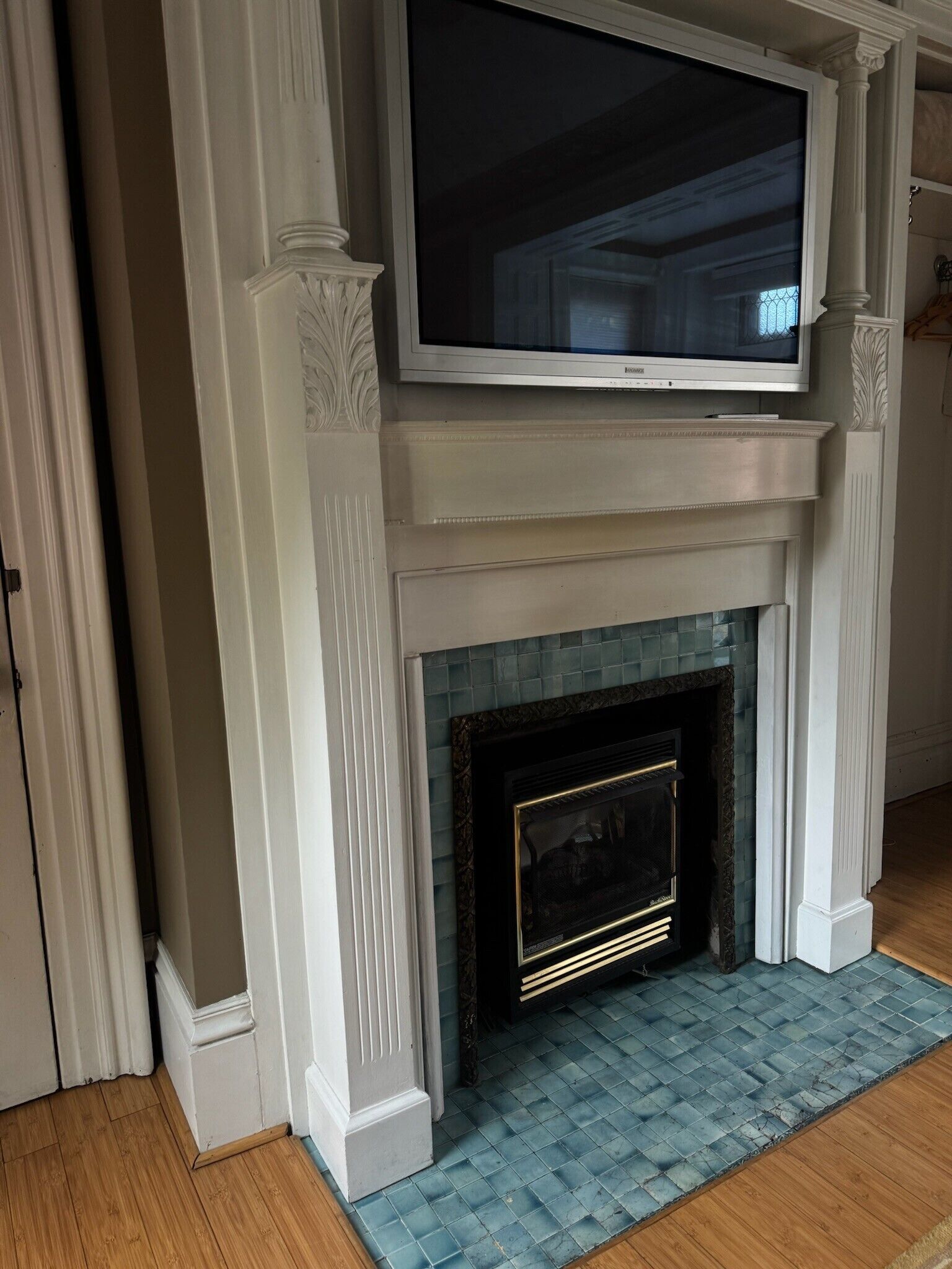 A room with a white fireplace, a television mounted above it, and a blue tiled floor.