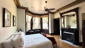 Un dormitorio con una cama grande, chimenea y ventilador de techo.