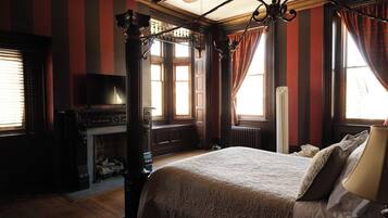 A traditional room with a four-poster bed, a fireplace, and a television.