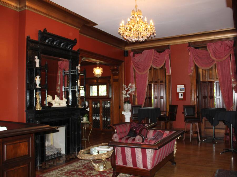 Een klassieke kamer met een open haard, een bank, een kroonluchter en een spiegel.