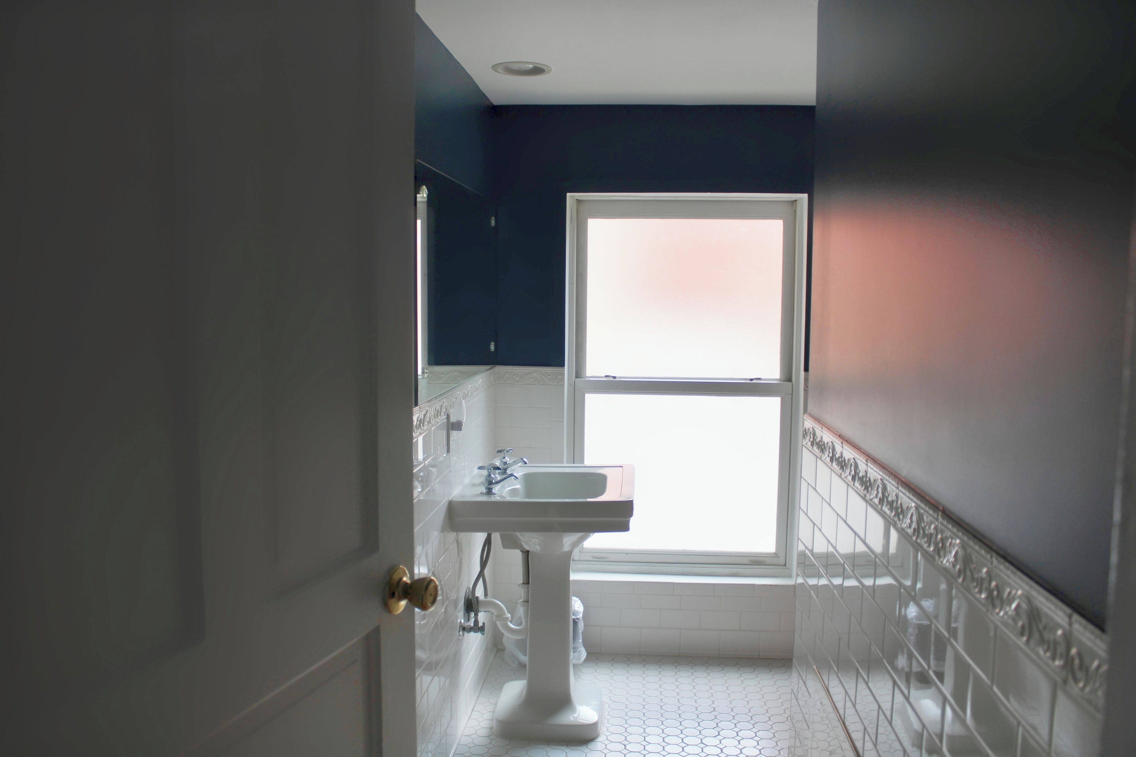 A bathroom with a white sink, a window, and a door.