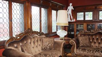 A room with two ornate sofas, a lamp, and a statue.