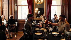 Un restaurante con paredes revestidas de madera, un espejo grande y cortinas rojas.
