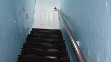 A staircase with black steps leading to a white door at the top.