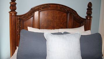 A bed with a wooden headboard, multiple pillows, and a white mattress.