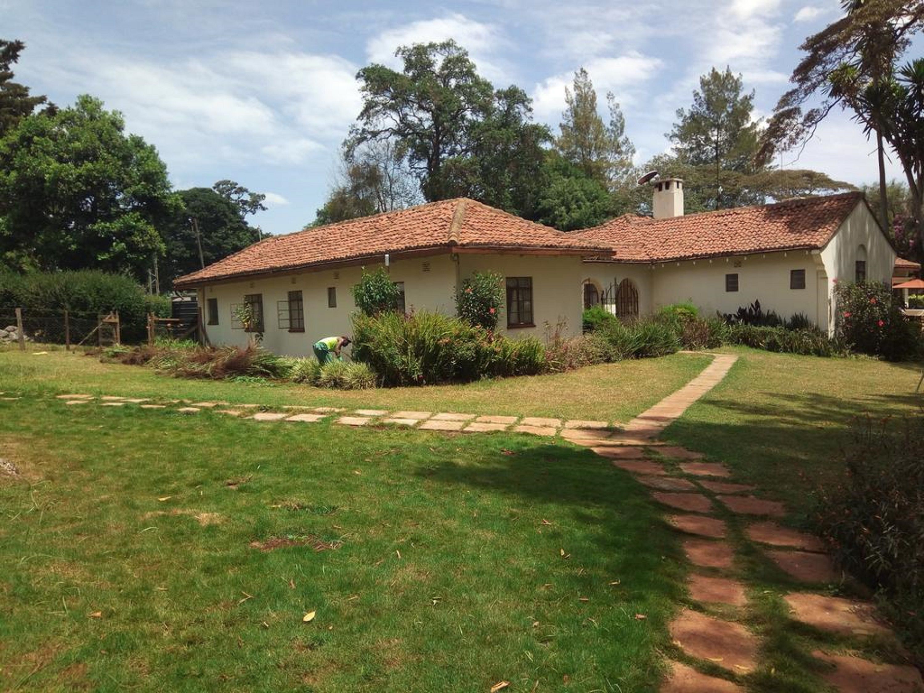 Una casa de un piso con techo de tejas, rodeada de un césped cuidado y un sendero de piedra que lleva a la entrada.