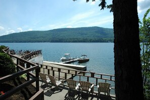 A lakeside deck with chairs and a dock with boats. - Park Lane Motel (Lake George)