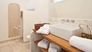 A modern bathroom with a freestanding bathtub, a wooden shelf with towels, and a shower area. - Le San Lorenzo  (Porto-Vecchio)