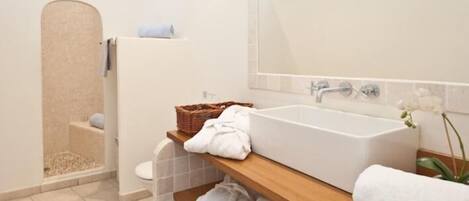 Un baño moderno con una bañera independiente, un estante de madera con toallas y una zona de ducha.
