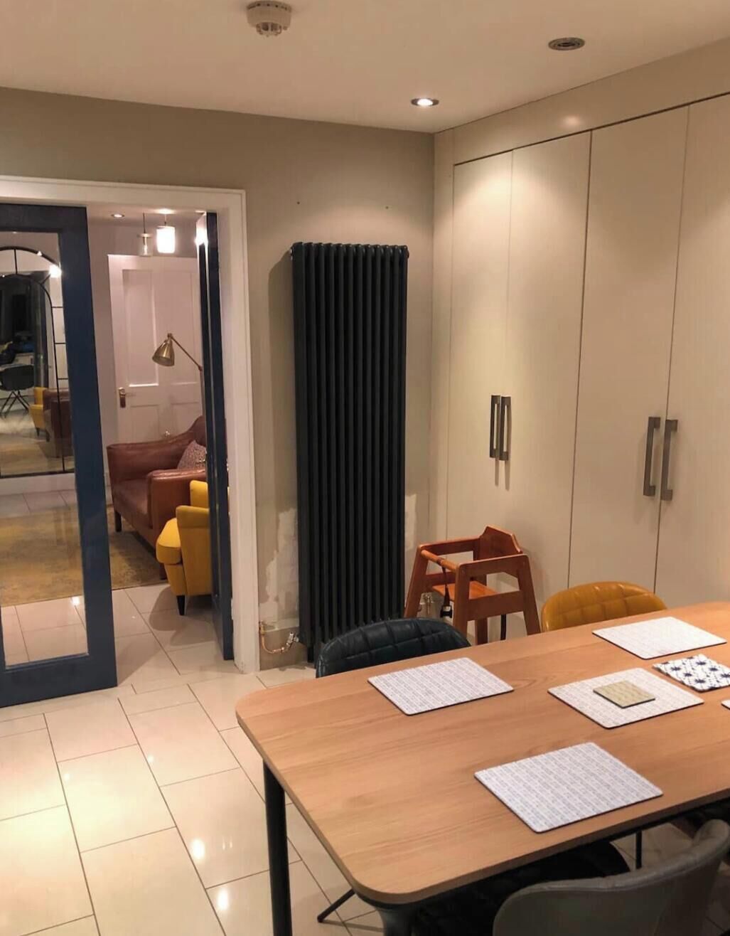 A room with a wooden table, chairs, a sofa, and a wardrobe.
