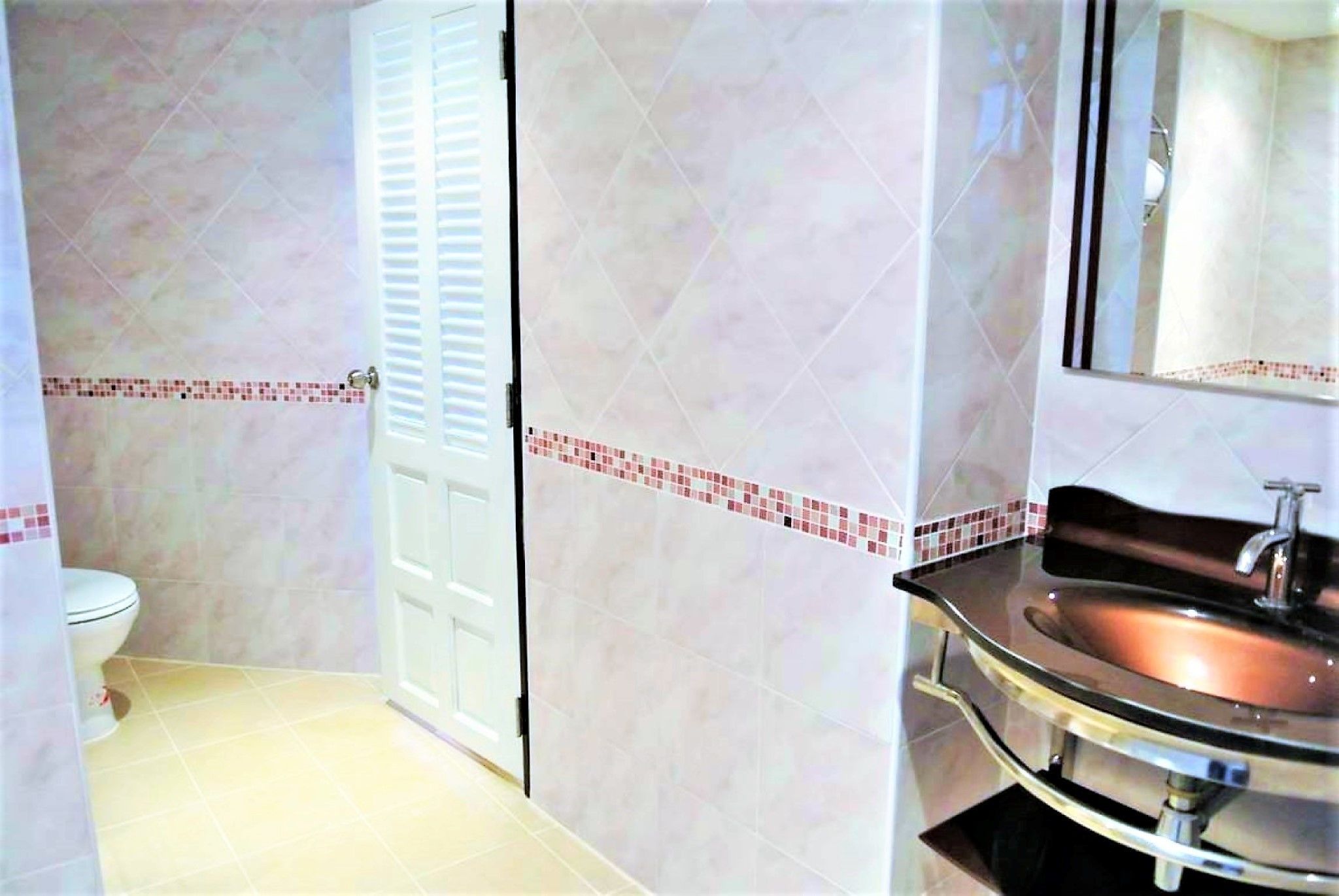 A bathroom with a toilet, a sink, and a mirror.