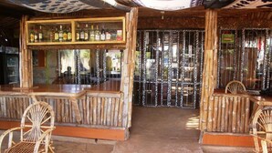 A rustic bar area with bamboo furniture and a display of liquor bottles. - Amboseli Getaway Hotel (Kimana)