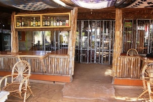 A rustic bar area with bamboo furniture and a display of liquor bottles.