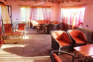 A room with wicker furniture, including chairs and a table, and a stone floor.