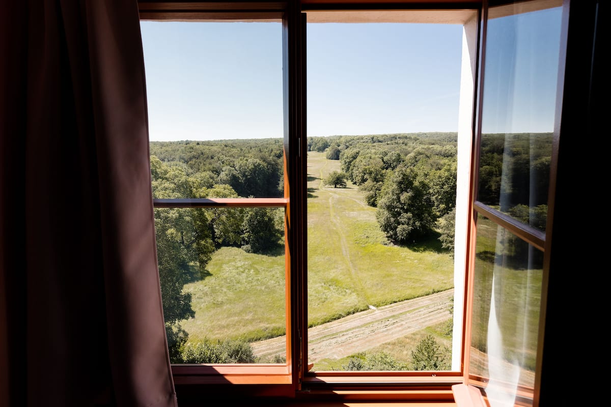 A room with a large window overlooking a forested area.